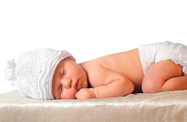 sleeping newborn baby girl in white hat wearing diaper stock photo