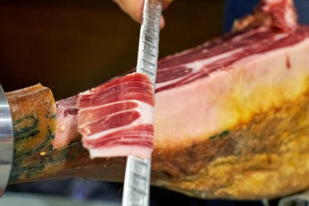 slice of acorn-fed Iberian ham held on the knife of the cutter. stock photo