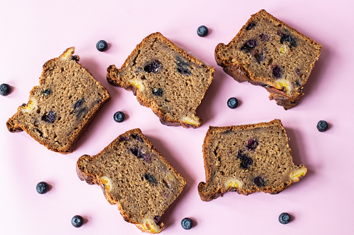Sliced banana bread with blueberries on pink background. Flat lay.