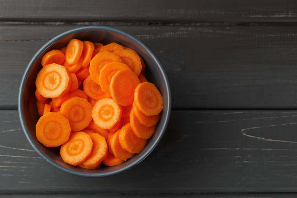Sliced carrots in a bowl on black background stock photo