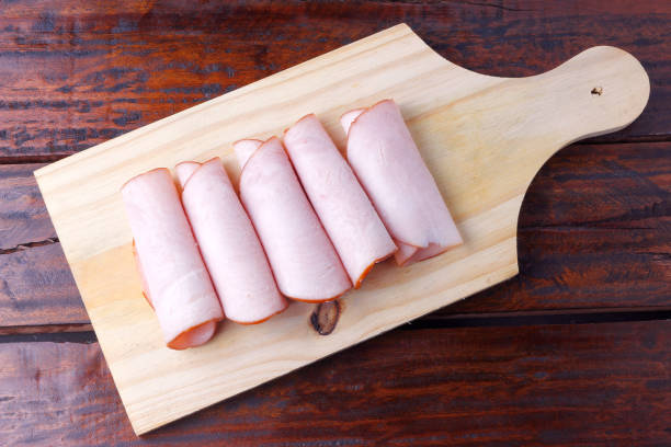 sliced cold smoked turkey breast over rustic wooden table. stock photo