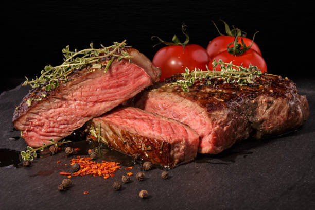 Sliced grilled beef steak with spices on slate slab stock photo