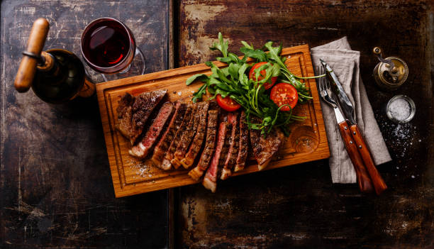 Plakjes gegrilde steak met een rucola salade en rode wijn​​​ foto
