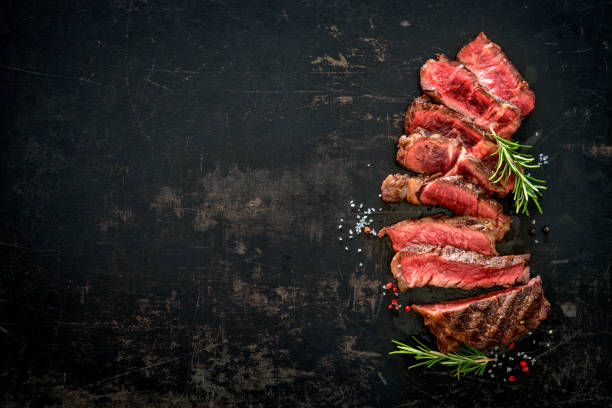 Sliced medium rare grilled beef ribeye steak Sliced medium rare grilled beef ribeye steak on dark background cooked meat stock pictures, royalty-free photos & images
