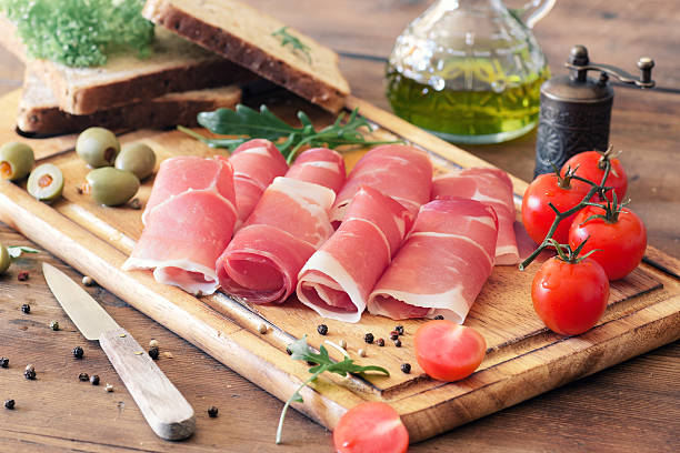 sliced prosciutto on a wooden board sliced prosciutto on a wooden board prosciutto stock pictures, royalty-free photos & images