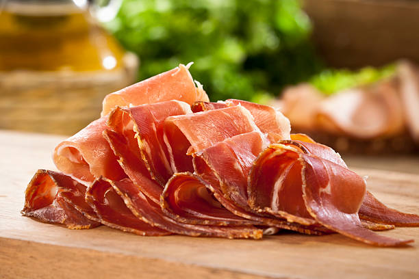 Sliced Prosciutto Sliced Italian Prosciutto on Wood Cutting Board prosciutto stock pictures, royalty-free photos & images