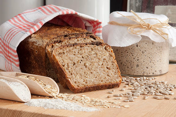 Sliced rye bread coveted in cloth next to oats and jar stock photo