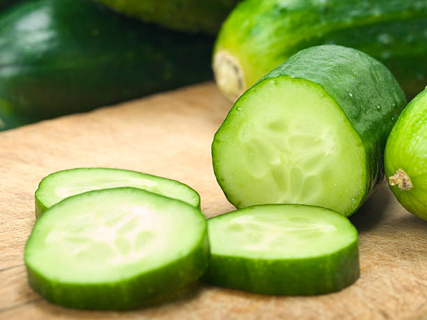 Sliced up cucumbers on wooden board stock photo