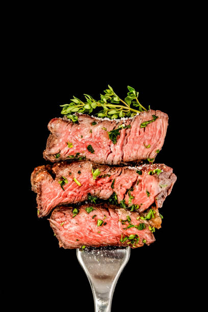 Slices of beef steak from grill with salt and herbs on a fork. stock photo