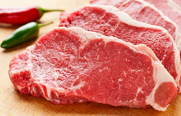 rodajas de bistec nueva york strip en tabla de cortar - carne de vaca fotografías e imágenes de stock
