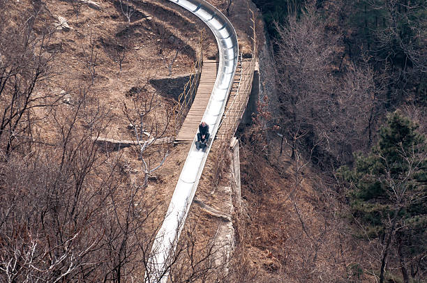 slide down from the great wall Beijing,China - March 30 ,2011 : Visitor use toboggan-run slide down in motion blur from the great wall of China at Mutianyu pass in Beijing,China.That is fast way and fun to come down. mutianyu stock pictures, royalty-free photos & images