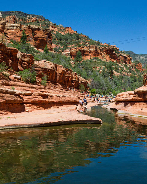 Slide Rock State Park "Slide Rock State Park, Arizona, United States - May 19, 2012. People enjoying the water at Slide Rock State Park on a hot summers day. Slide Rock is a natural water slide in Oak Creek Canyon and draws many tourists every year." state park stock pictures, royalty-free photos & images