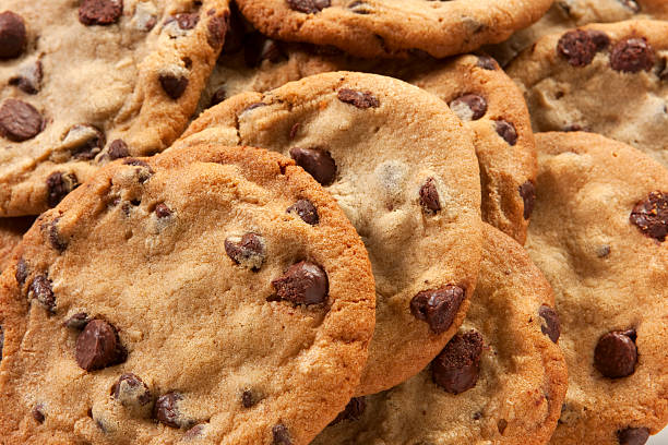 Slightly overdone chocolate chip cookies in a messy pile A plate of freshly baked chunky chocolate chip cookies. cookie stock pictures, royalty-free photos & images