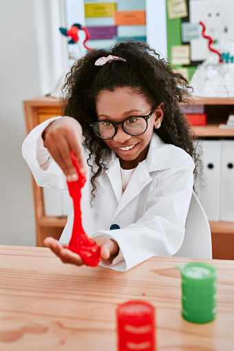 Shot of an adorable young school girl playing and experimenting with slime in science class at school
