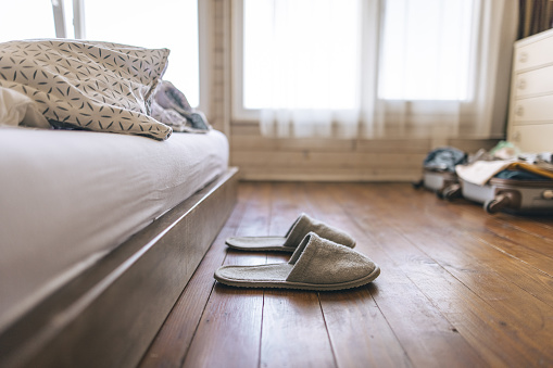 Slippers on hardwood floor on bedside