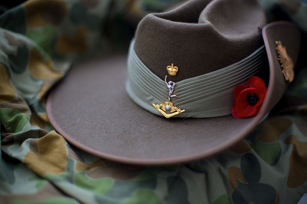 Australian Army slouch hat with red poppy resting on an auscam background.