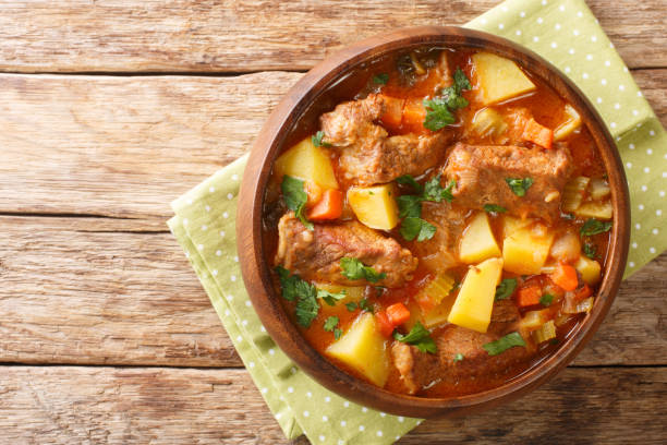 Slow beef stew with wine, potatoes, carrots and celery close-up in a bowl. horizontal top view stock photo