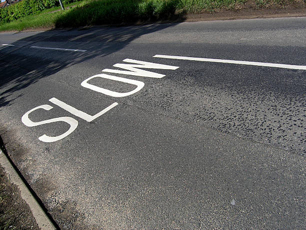 Slow! Slow lettering on an English road. skeable stock pictures, royalty-free photos & images