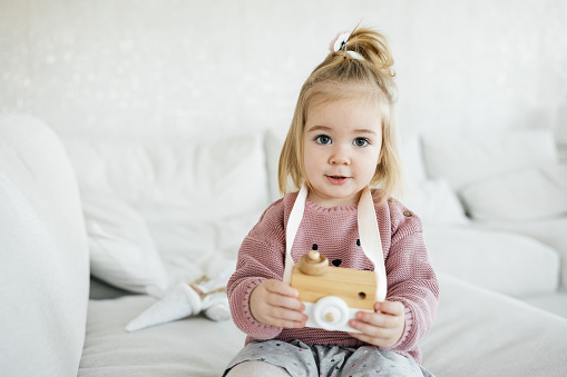 Small adorable girl holding wooden toy camera