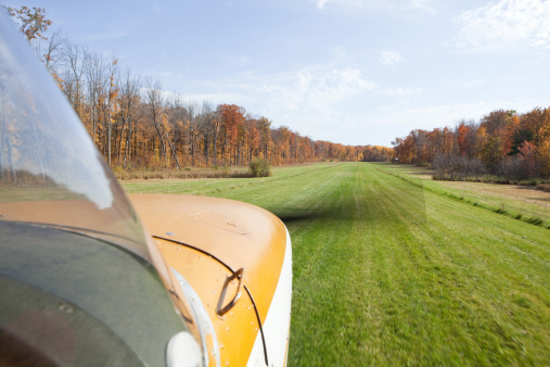 Small Airplane Landing on a Grass Strip with Fall Trees