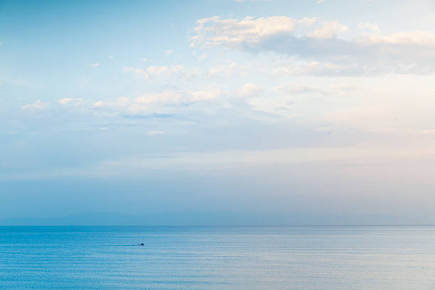 Small boat goes on sea water, negative space Seascape under cloudy blue sky, small boat goes on sea water, negative space composition altostratus stock pictures, royalty-free photos & images