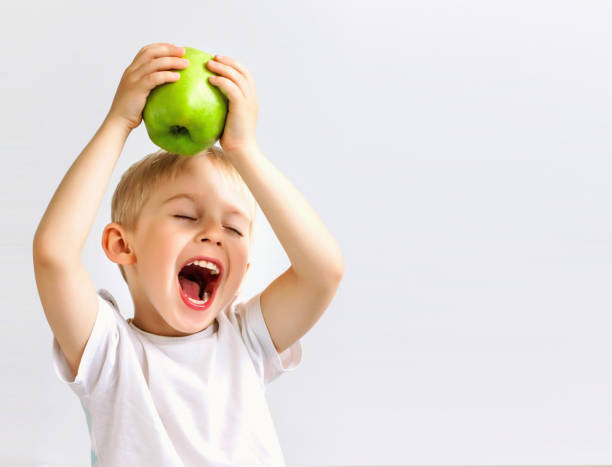 small boy holds a big green apple, stock photo