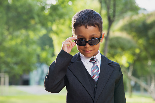 Small boy in black suit and black sunglasses.