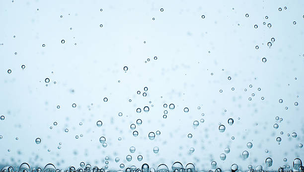 Small bubbles of oxygen on blurred blue background - liquid oxygen stock photo