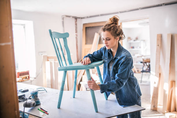 Small business of a young woman. Small business of a young woman. Beautiful young woman worker in carpenter workroom. Old furniture restoration. restoring stock pictures, royalty-free photos & images