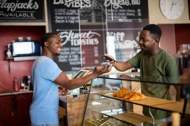 Small business owner using contactless payment with customer in cafe stock photo