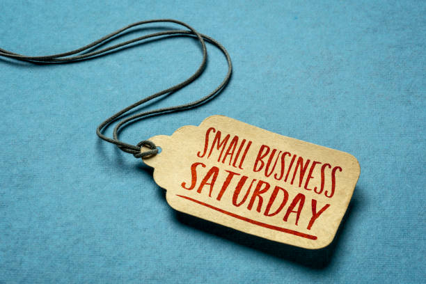 Small Business Saturday text on a price tag Small Business Saturday sign - a paper price tag with a twine against blue paper background, local holiday shopping concept small business saturday stock pictures, royalty-free photos & images
