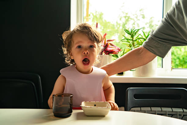 Small child choked on food eating in the kitchen indoors Portrait of a small child choked on food eating in the kitchen and a parent slaps his hand on the back choking photos stock pictures, royalty-free photos & images