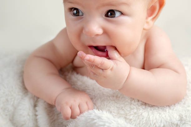 Small cute funny baby infant teething with face expression hands and fingers in mouth sore gums Small cute funny baby infant teething with face expression hands and fingers in mouth sore gums soothe newborn Teeth stock pictures, royalty-free photos & images