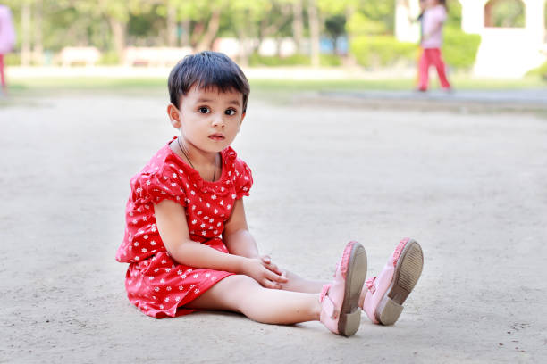 Small cute girl sitting in public park stock photo