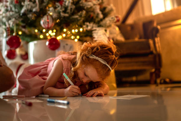 small cute girl writing letter to santa at home - a letter to santa claus, christmas gifts imagens e fotografias de stock