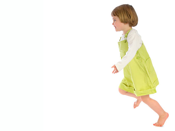 Small girl in dress running across white background stock photo