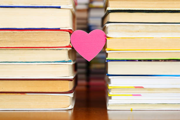 A small heart and books A small heart hangs between two piles of old books. romance book cover stock pictures, royalty-free photos & images