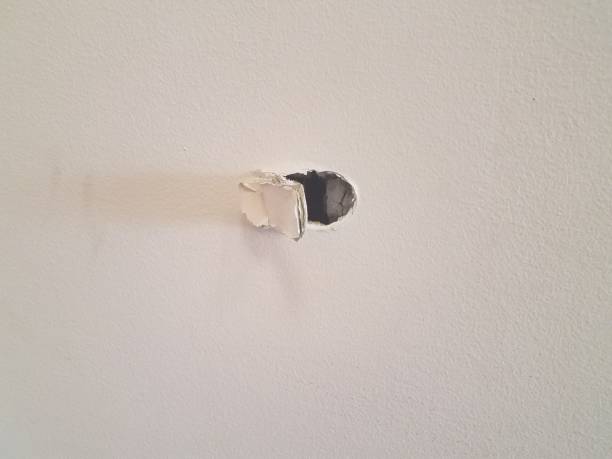 small hole damage in a drywall wall stock photo