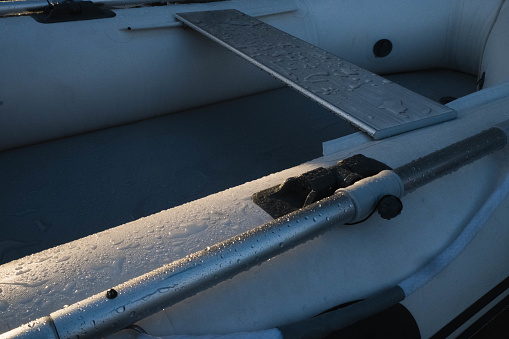 Close up shot of an inflatable and aluminum dinghy/boat showing oars, seating and rope at sunset