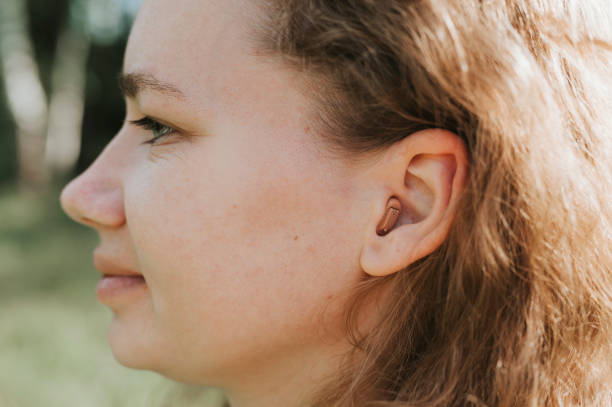 bir kadının kulağında küçük kanal içi işitme cihazı - hearing aids stok fotoğraflar ve resimler