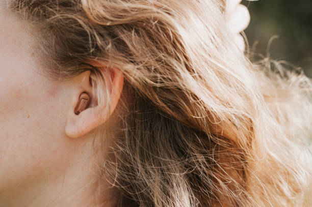 bir kadının kulağında küçük kanal içi işitme cihazı - hearing aids stok fotoğraflar ve resimler