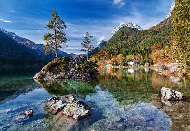 Small island reflected in calm Hintersee lake at clear autumn morning, Berchtesgaden park, Germany. stock photo