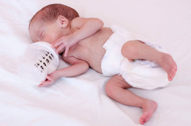 bir şişe süt formülü yeme bir küçük prematüre bebek - baby formula stok fotoğraflar ve resimler