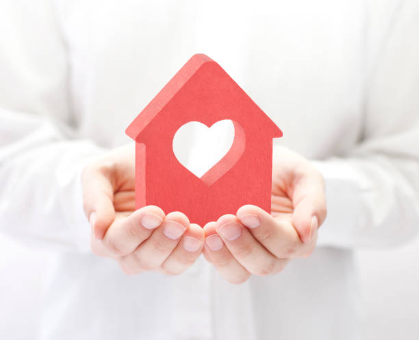 Small red house with heart in hands stock photo