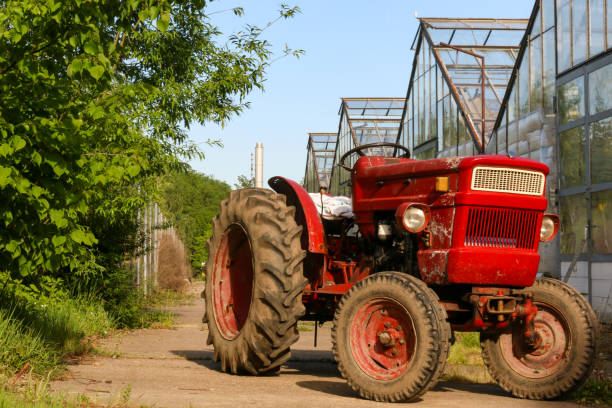 Small red tractor next to the greenhouses of a nursery stock photo