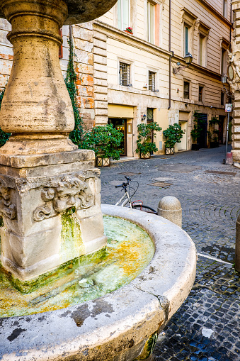 The small square of San Simone with a 16th century fountain along Via dei Coronari in the historic center of Rome. Called Via Recta in medieval times, Via Dei Coronari was one of the main entrances to St. Peter's Basilica from the center of Rome and from the Port of Ripetta, on the Tiber river. Among its Renaissance buildings you can admire the house of the painter Raphael. This ancient street, frequented by tourists for its typical antique shops and Roman cuisine restaurants, is still an important pedestrian route between the area of St. Peter's Basilica and the Roman Pantheon district. Image in high definition format.