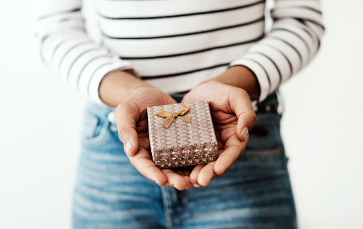 Cropped shot of a woman holding a gift box against a studio background