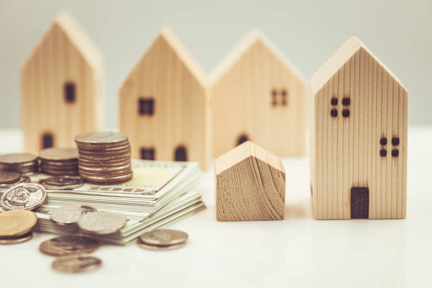 Small wooden home with money for buying new bigger home or house expenses concept. stock photo
