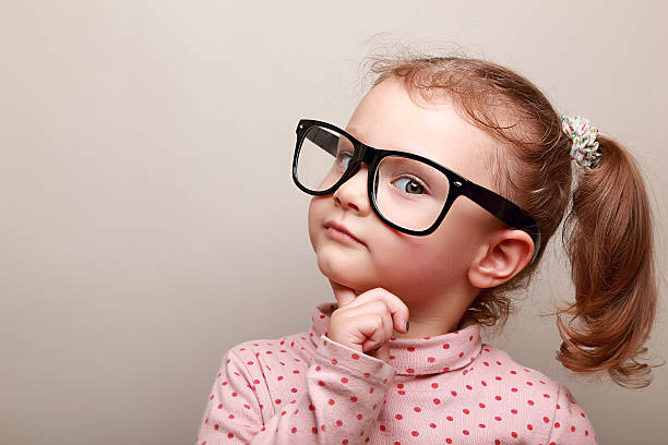 Smart dreaming kid girl in glasses looking stock photo