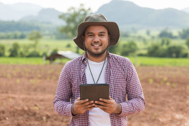 Smart farmer using a technology for studying and development agricultural. The farmer using tablet for tests the growth quality of seedling. stock photo